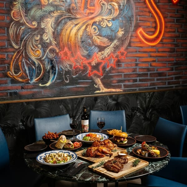 A table laden with various dishes including chicken, steak, burgers, and wraps, in a restaurant.